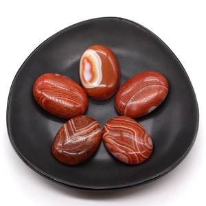 Polished red banded agate oval cabochons arranged in a black tray for DIY jewelry