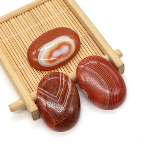 Macro view of three oval red striped agate stones on a bamboo mat background