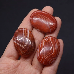 Polished oval striped agate stones in warm orange and white for DIY jewelry making