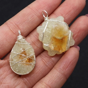 Handmade citrine crystal pendants wrapped in silver wire held to show size and texture