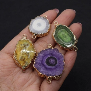 Macro-opname van vergulde natuurlijke druzy agaat hangers in vier kleuren op de hand