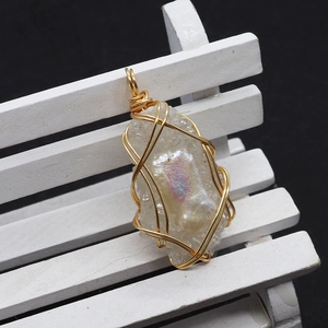Macro view of gold wire wrapped pendant with white quartz and iridescent natural pearl