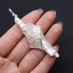 Détail d'un pendentif fait main en perle baroque et cristal blanc brut entouré de fil