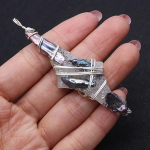 Détail d'un pendentif fait main en fil de cristal et perles baroques sur paume