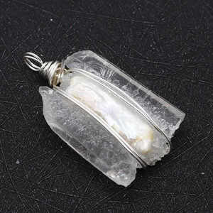 Macro detail of natural clear quartz and baroque pearl pendant with silver wire wrap