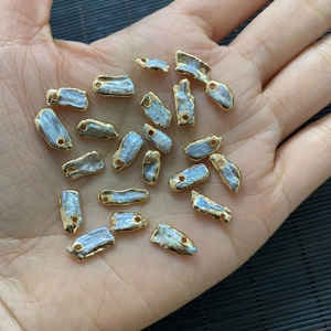 Hand holding natural baroque pearl pendants with gold plated edges for DIY jewelry making