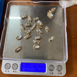 Detailed view of irregular baroque pearl pendants with gold edges on an electronic scale