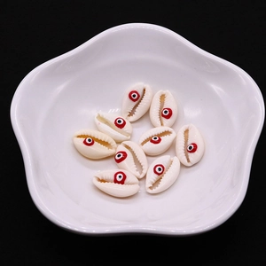 Primer plano de cuentas de concha natural con patrón de ojo turco en plato blanco