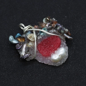 Macro shot of handmade wire wrapped pendant with red crystal and baroque pearls