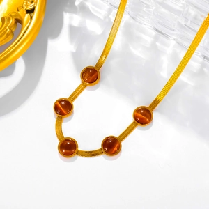 Macro shot of 18k gold plated flat snake chain necklace with five round brown cat eye stones