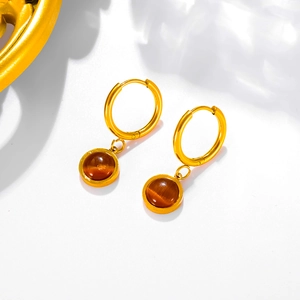 Detail view of golden hoop earrings with round tiger eye stones and polished finish