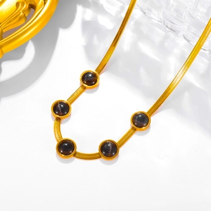 Detailed macro of gold snake chain necklace featuring five circular dark cat-eye stones