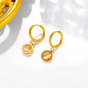 Detailed macro view of gold hoop earrings with cat-eye gemstones and sleek titanium finish