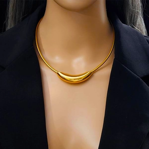 Gold-toned crescent pendant snake chain necklace styled with a black blazer on a model
