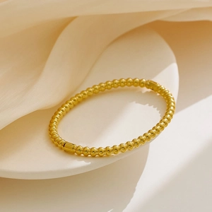 Minimalist 18k gold plated stainless steel bead bracelet on a beige silk background