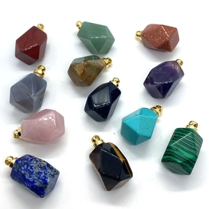 Macro shot of twelve faceted gemstone pendants featuring gold-plated bails on white backdrop