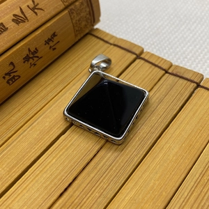 Detailed macro view of black onyx square pendant with intricate hollow metal engraving