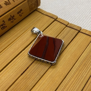 Macro detail of natural red jasper stone pyramid pendant with ornate silver filigree frame