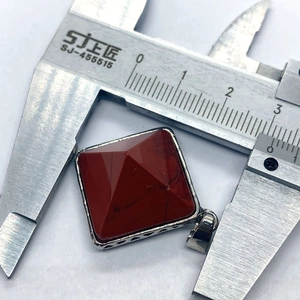 Measuring the red stone pyramid pendant with a caliper to show the 20mm size and texture