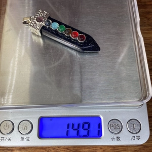 Gros plan d'un pendentif sept chakras de 14,91g en cours de pesage sur une balance