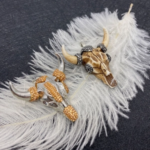 Détails de pendentifs tête de buffle avec cristaux sur fond de plume blanche