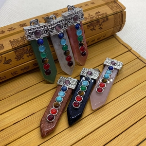 Détail de pendentifs sept chakras en cristal avec capuchons argentés sur fond bambou