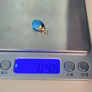 Detailed scale view showing the weight of a teardrop turquoise stone pendant with gold clasp