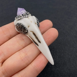 Detailed macro view of white bird skull pendant with purple crystal and black rhinestones