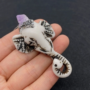 Detailed view of hand-held white elephant pendant with purple crystal and rhinestones