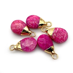Macro shot of faceted pink spotted stone waterdrop pendants with gold metal caps