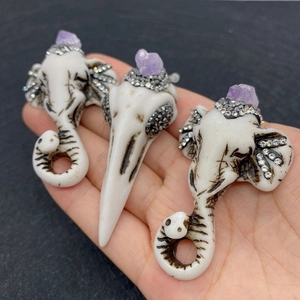 Macro detail of elephant skull pendants with purple crystals and sparkling rhinestones