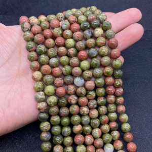 Natural unakite round stone beads strand held in hand for DIY jewelry making
