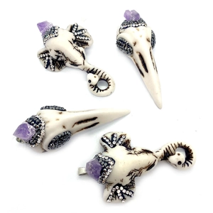 Detailed shot of resin elephant and bird skull pendants with purple crystal and rhinestones
