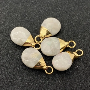 Detailed view of five teardrop pendants with white stone and golden metal caps