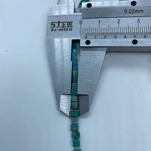 Detailed measurement of turquoise cube beads showing a precise 4mm size on digital caliper
