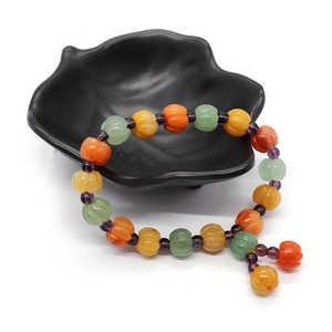 Natural stone pumpkin beaded bracelet with colorful topaz and white agate on a black plate