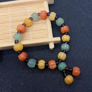 Detail of pumpkin-shaped natural stone beads in green, orange, and yellow with purple spacers