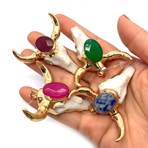 Detail of bohemian bull skull pendants with colorful gemstones and gold-plated edges