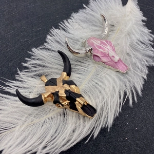 Ethnic bull skull pendants in pink and black with gold accents on white feather