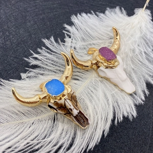 Bohemian bull skull pendants with natural stones and gold tips on a white feather