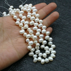 Hand holding strands of high-luster natural freshwater pearls for jewelry making