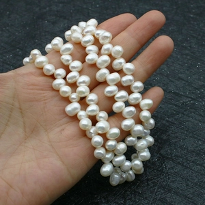 Close-up of hand holding a strand of high-luster natural freshwater baroque pearls