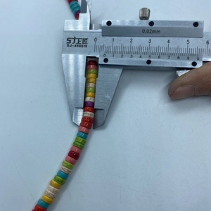 Macro shot measuring 4mm diameter of colorful stone spacer beads with a caliper tool