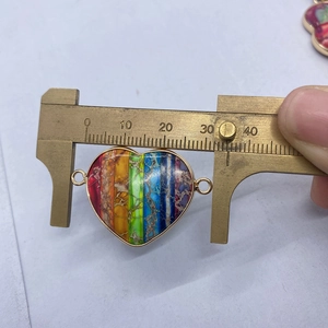 Detail showing rainbow heart stone connector with gold rim measured by a caliper
