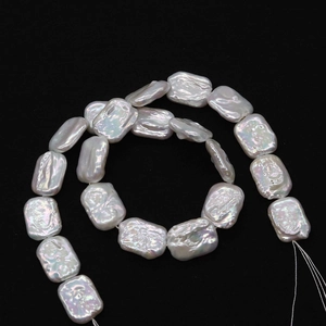 Strand of natural white baroque rectangular freshwater pearls on a dark textured background