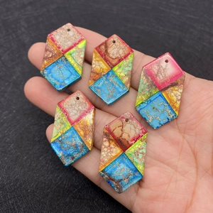 Five colorful hexagonal natural imperial jasper stone pendants held in hand for jewelry making