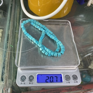 Detailed view of turquoise square beads on a digital scale weighing 20.71 grams