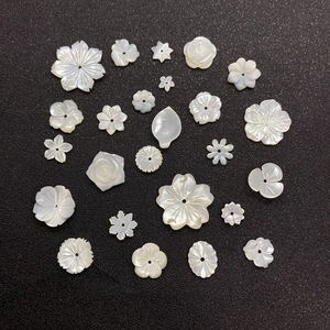 Macro detail of hand-carved white mother-of-pearl shell flower beads for DIY jewelry making