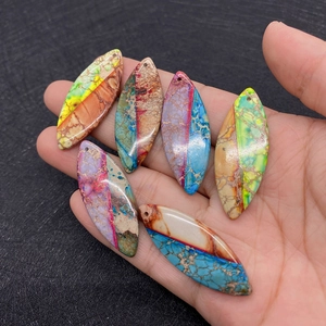 Hand holding six colorful rice-shaped natural stone pendants for DIY jewelry making