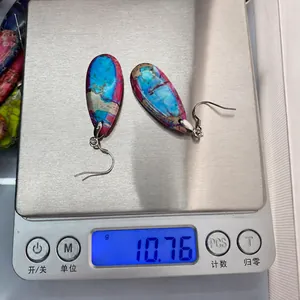 Detailed view of 10.76g teardrop stone earrings with blue and red marble texture on a scale